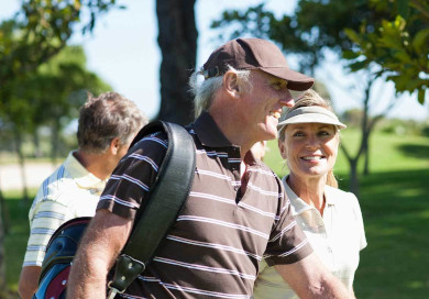 A mature couple smiles while walking the golf course